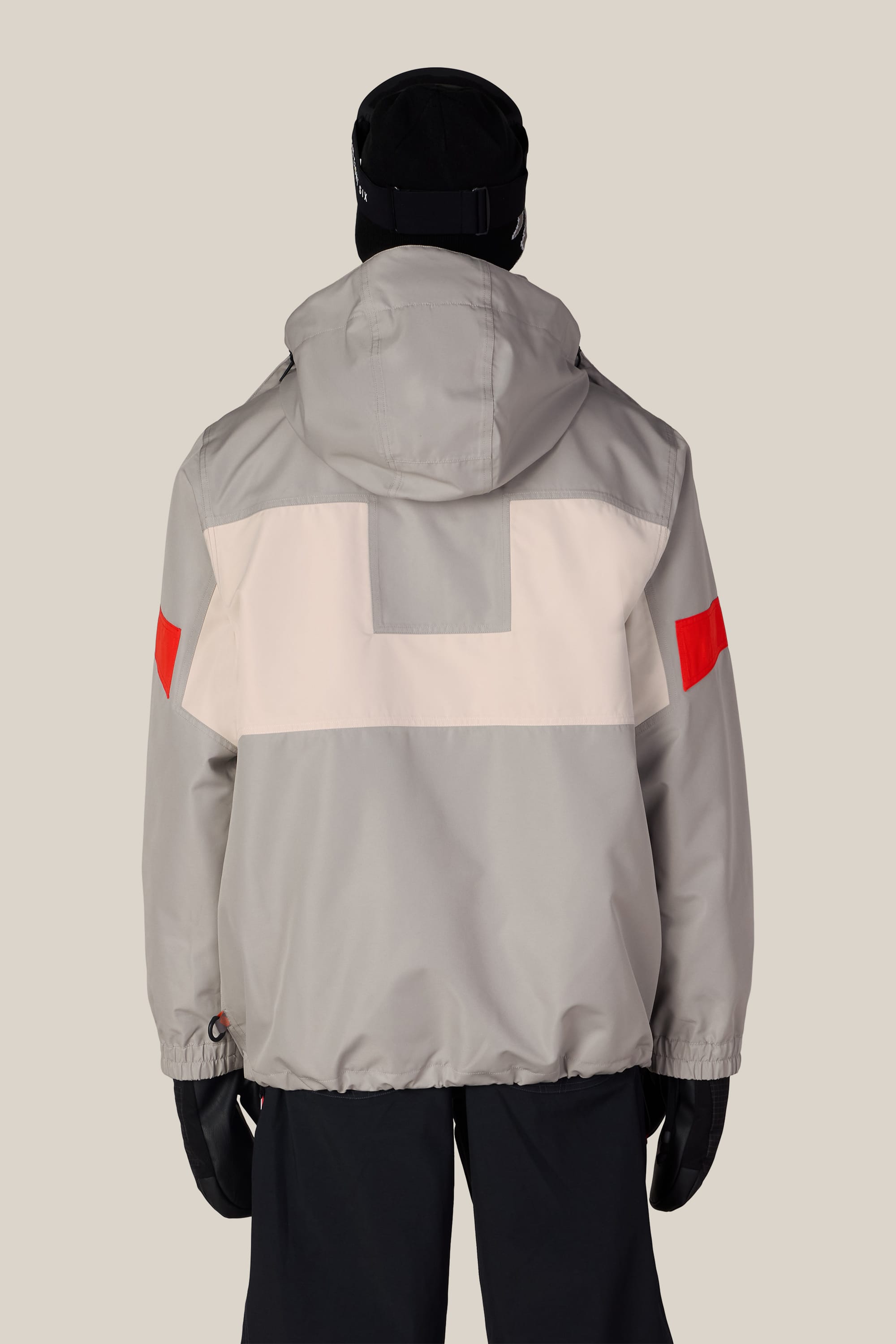 A person is shown from behind against a plain background, wearing the 686 Men’s 2001 Logic Jacket by 686—a light gray woven jacket featuring a white back panel and red accents on the sleeves—paired with black gloves, black pants, and a black hat.