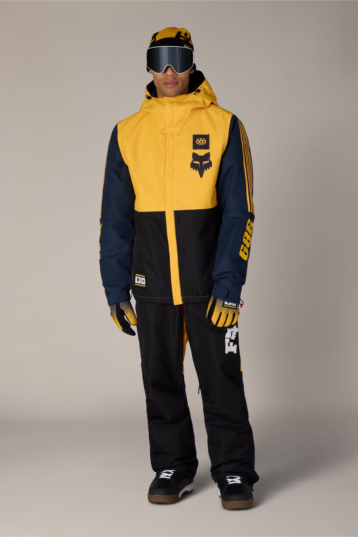 A person wearing a 686 Men’s Fox Racing Spec Insulated Jacket with matching pants, gloves, beanie, and goggles.