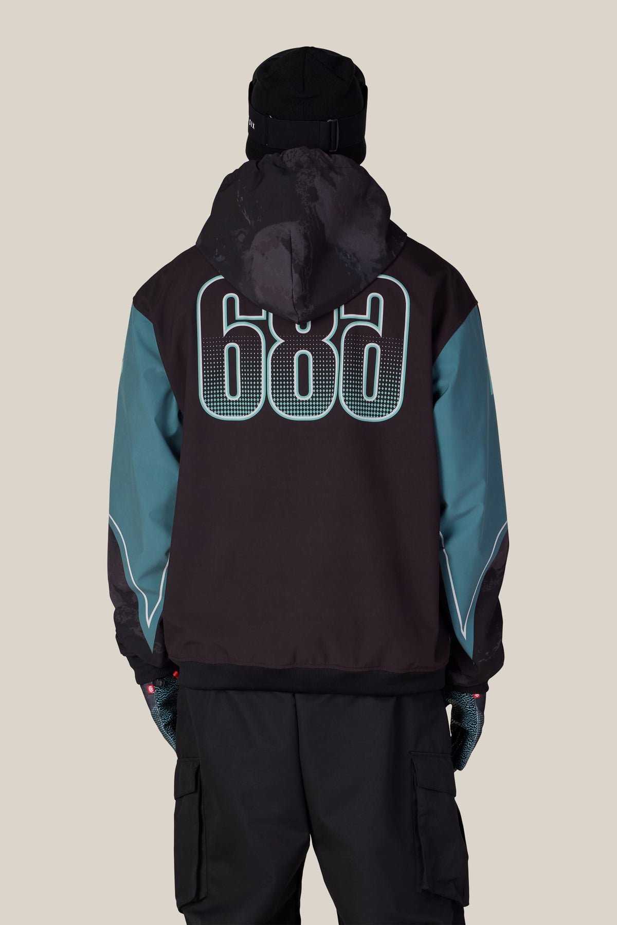A person viewed from behind wearing a black beanie and a 686 Men’s Fox Racing Waterproof Team Hoody.