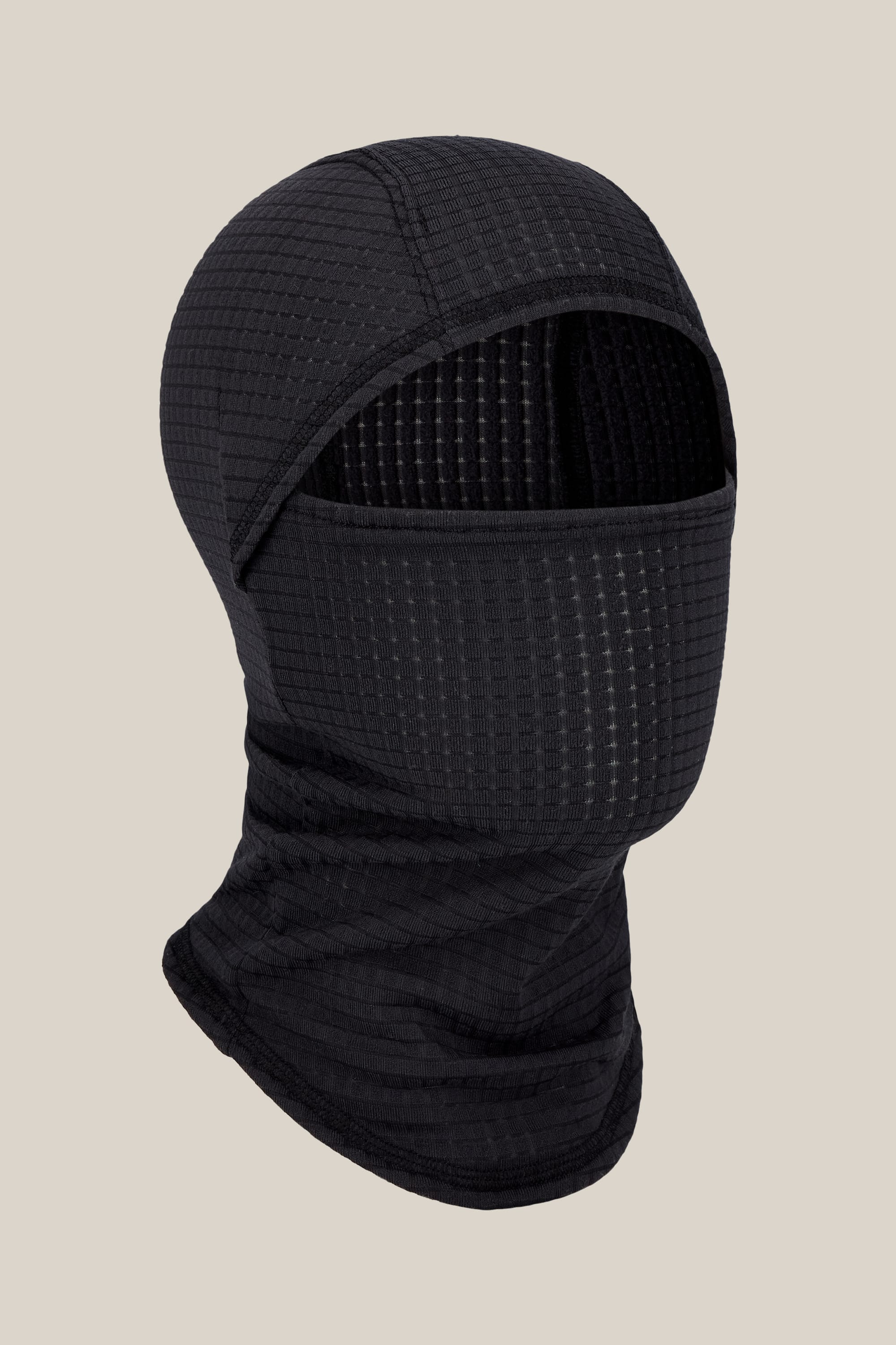 The 686 Mission Grid™ Balaclava by 686 is a black, textured knit facemask featuring a face opening, shown against a plain beige background.