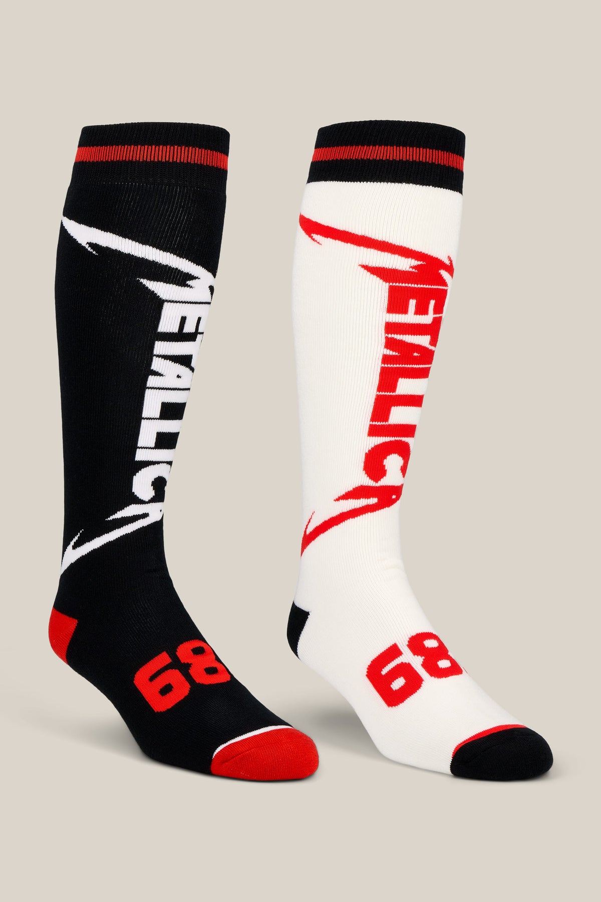 A 2-pack of 686 Men’s Metallica Socks featuring two knee-high performance socks, one black and one white, each with the Metallica logo in contrasting colors and the number 68 on the foot.