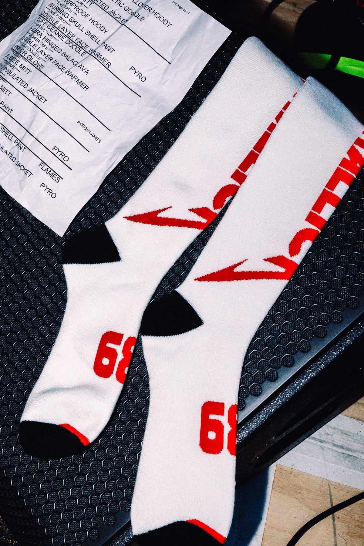 Two white acrylic 686 Men’s Metallica Socks - 2-Pack crew socks with red graphics, featuring the Metallica logo on the calf and the number 68 on the foot.
