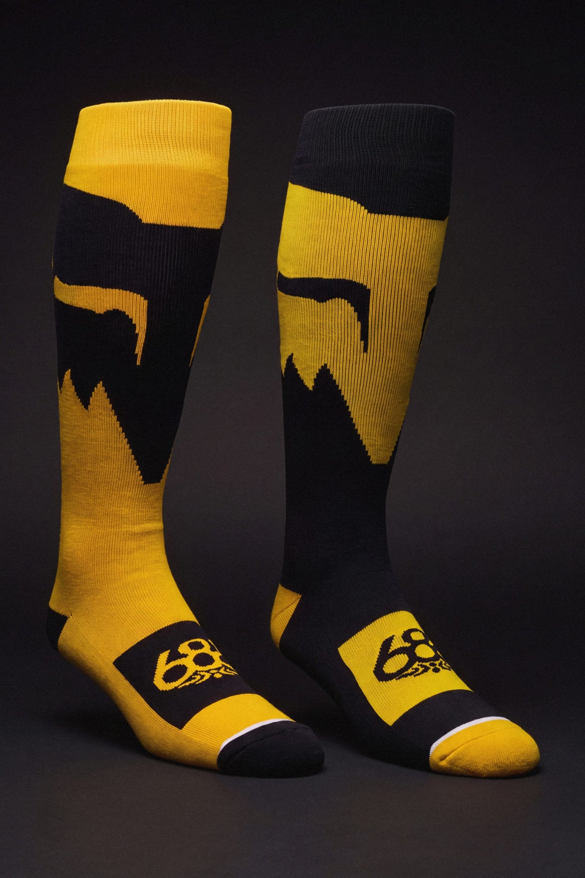 A pair of black and yellow 686 Men’s Fox Racing Socks - 2-Pack featuring a fox head logo and the number 68 on the foot.
