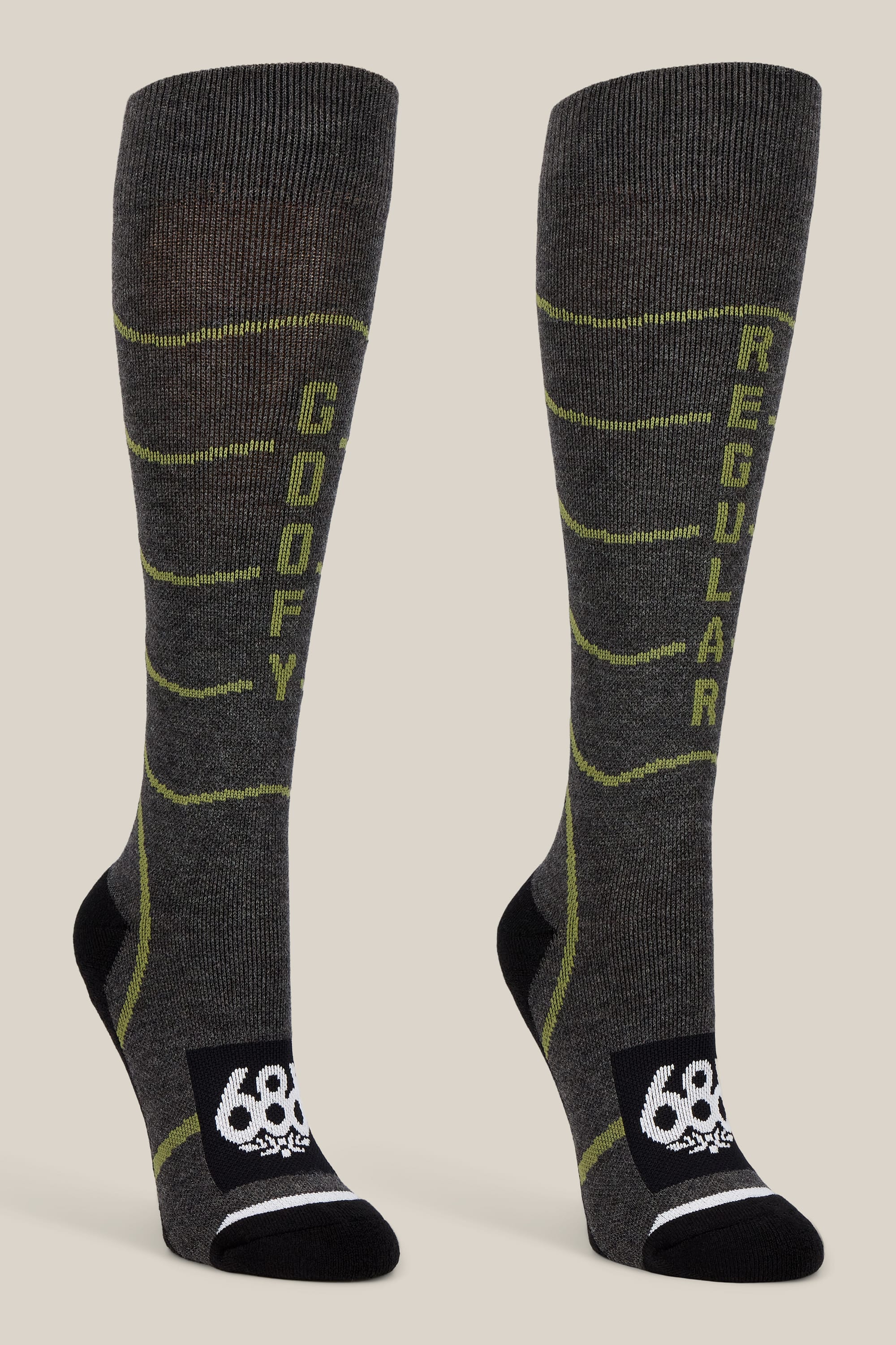 The 686 Women’s Contour Merino Sock - 2-Pack by 686 features a pair of gray knee-high performance socks for women, designed with yellow-green accents. The left sock is labeled “GOOFY” while the right reads “REGULAR.” Both socks showcase a black toe and heel area, a white 686 logo on the foot, and are crafted for both comfort and style.