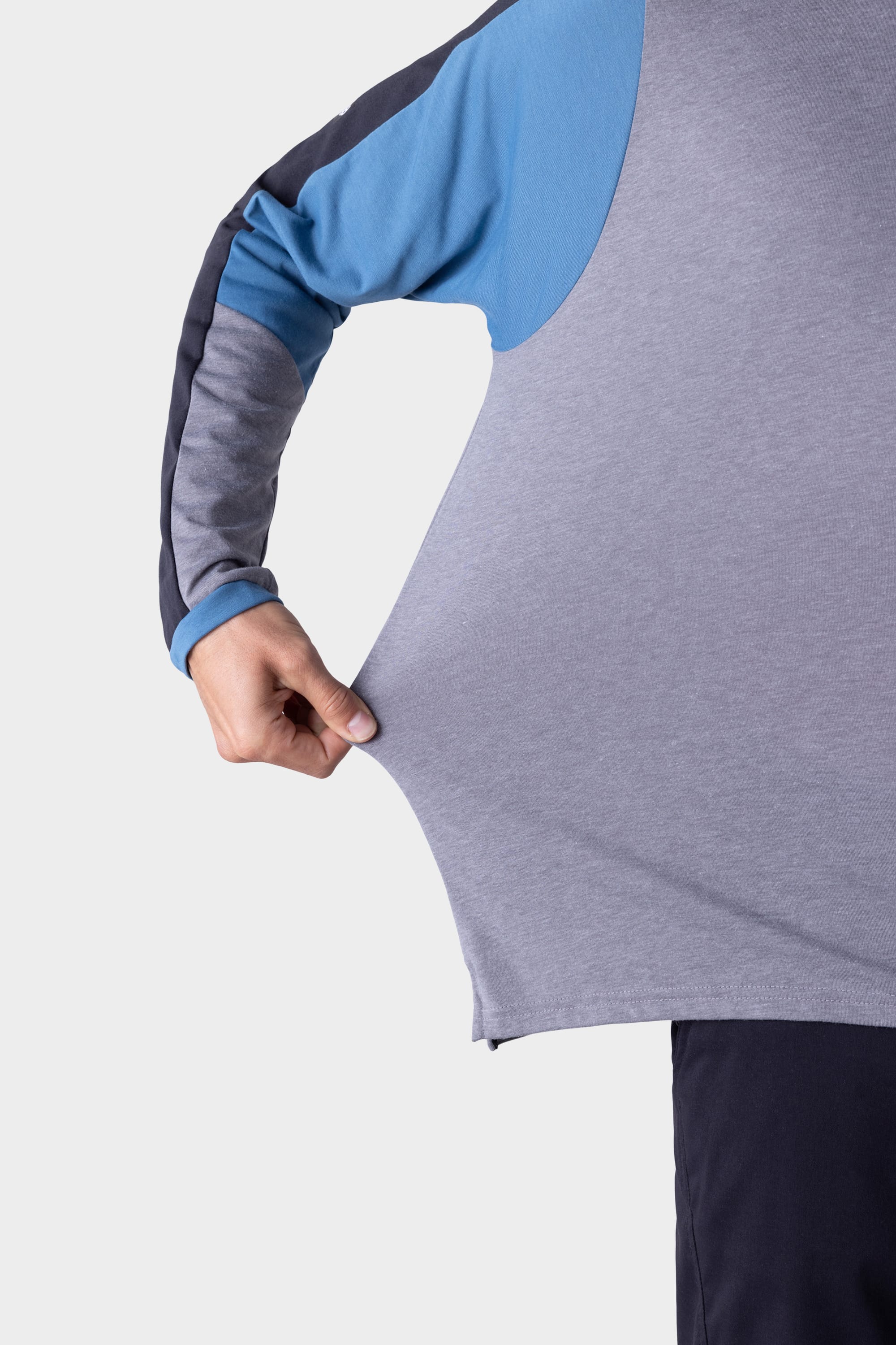 A man wearing the 686 Mens Rival Long Sleeve Bike Jersey stretches the gray fabric with his left hand, demonstrating the jerseys flexibility.