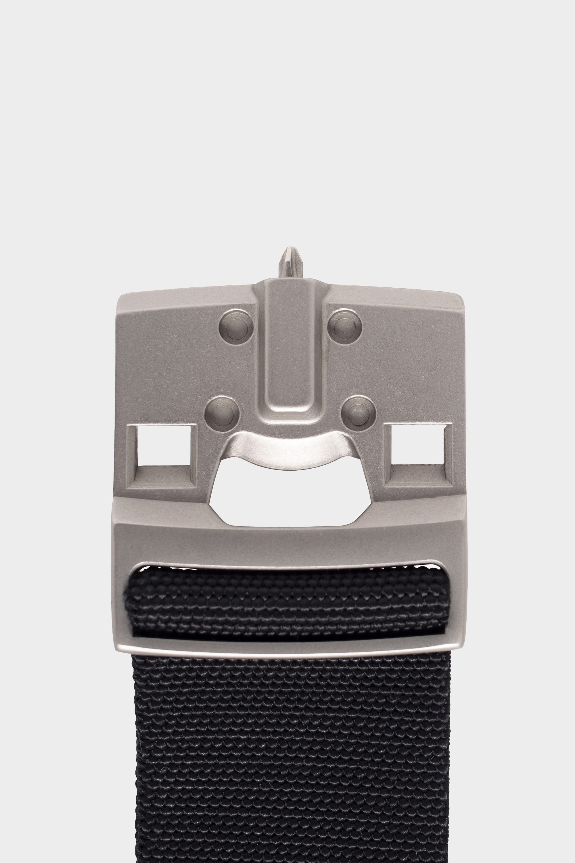 A close-up of the 686 Westwell Clicker Stretch Belt by 686, featuring a metallic buckle with a stylized face design on a black fabric strap, set against a plain white background.